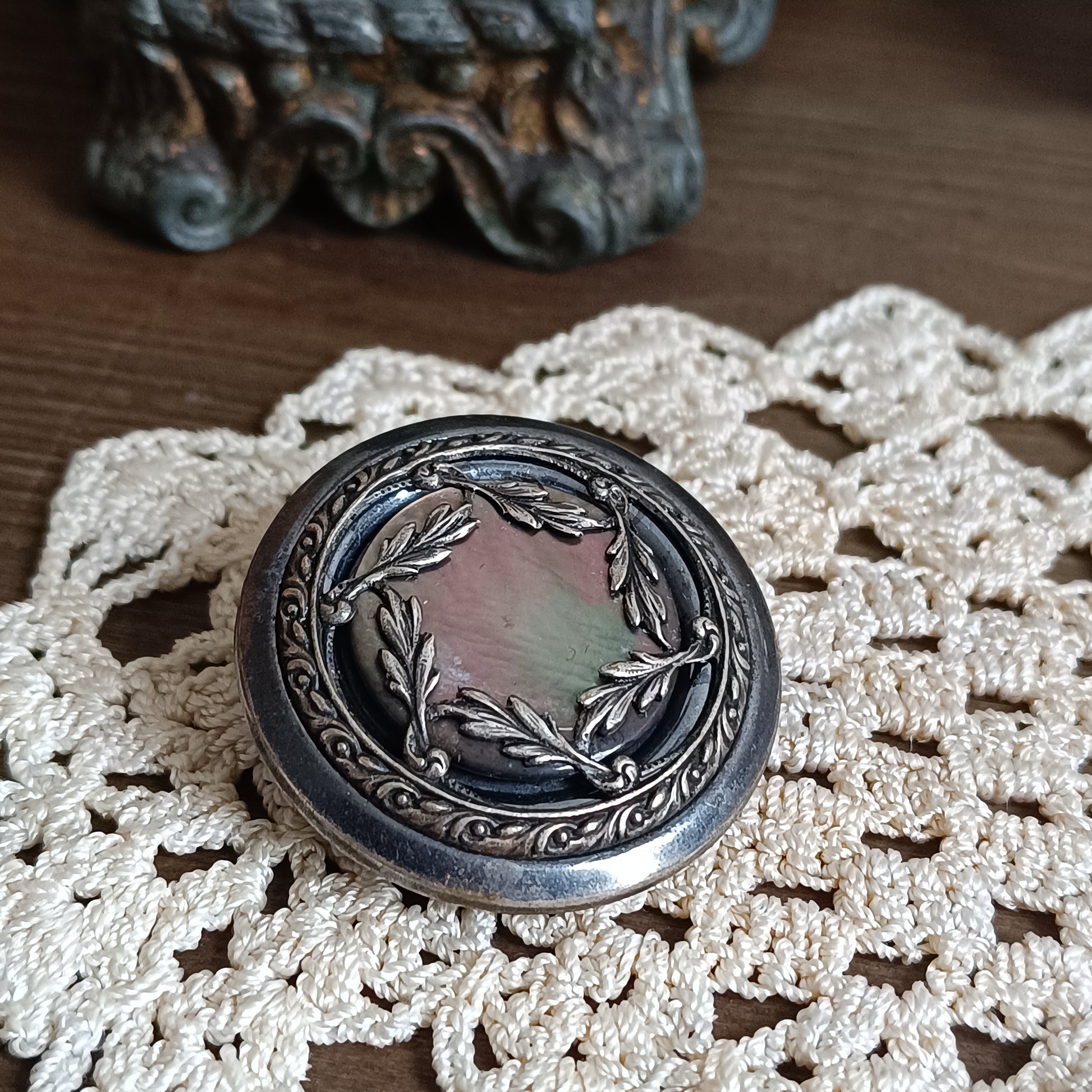 Broche vintage en nacre irisée avec couronne de laurier en métal bronze, créée à partir d’un bouton français des années 1930 gravé Paris. 