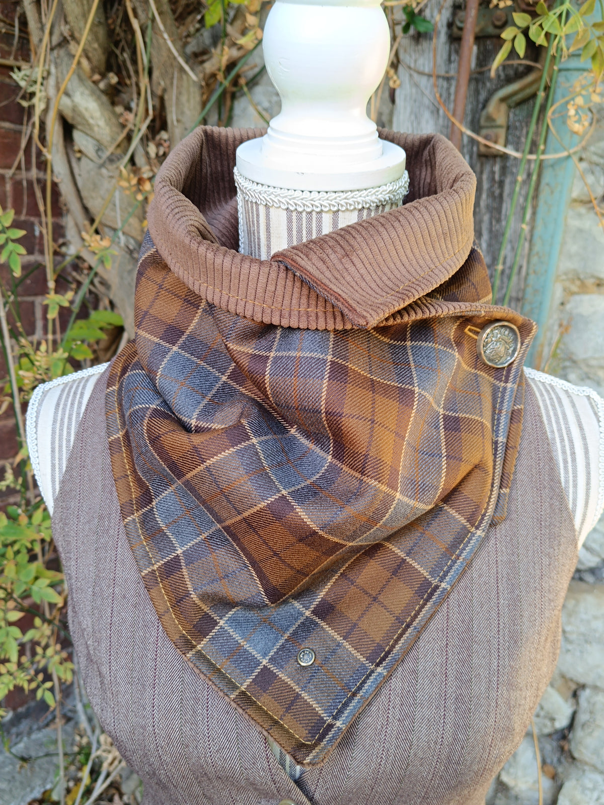 Tour de cou en tartan marron et bleu, revers en velours côtelé brun et bouton blason héraldique, alliant caractère et élégance rétro britannique