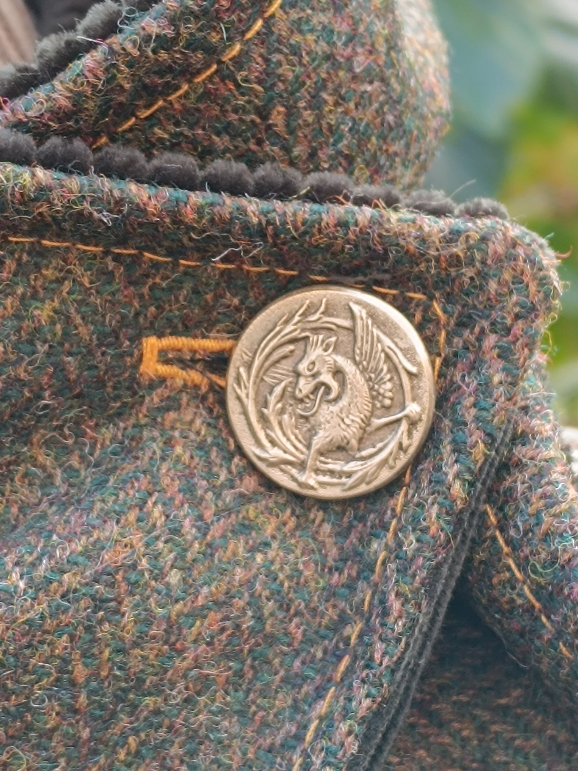 Bouton vintage dragon sur tweed multicolore aux reflets verts, bruns ocre. Surpiqûres et boutonnière jaune ocre. Détail artisanal unique, idéal pour veste ou accessoire textile au style bohème, féerique ou cottagecore. Élément décoratif fait main, parfait pour une création spéciale en boutique française.