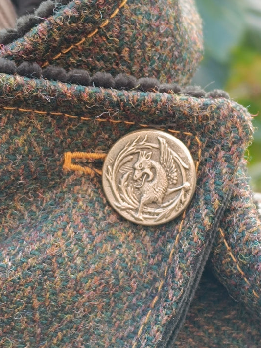 Bouton vintage dragon sur tweed multicolore aux reflets verts, bruns ocre. Surpiqûres et boutonnière jaune ocre. Détail artisanal unique, idéal pour veste ou accessoire textile au style bohème, féerique ou cottagecore. Élément décoratif fait main, parfait pour une création spéciale en boutique française.