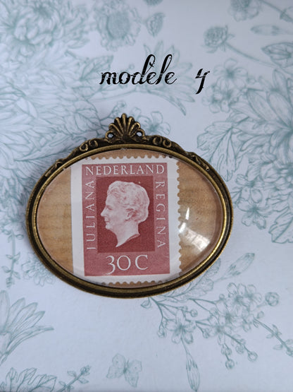 Broche ovale encadrant un timbre néerlandais vintage rouge du siècle dernier, illustré du profil de la reine Juliana et marqué "NEDERLAND JULIANA REGINA 30C", avec oblitération visible. Présentée sur un fond fleuri aux tons doux.