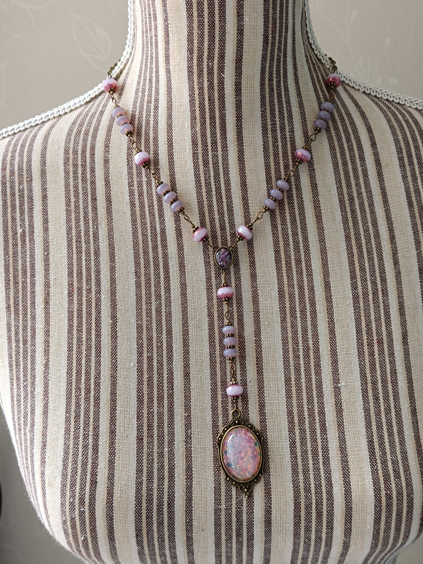 Détail du connecteur de collier vintage : petit cabochon en verre Silver Foil violet, perles opaline roses et laiton antique.