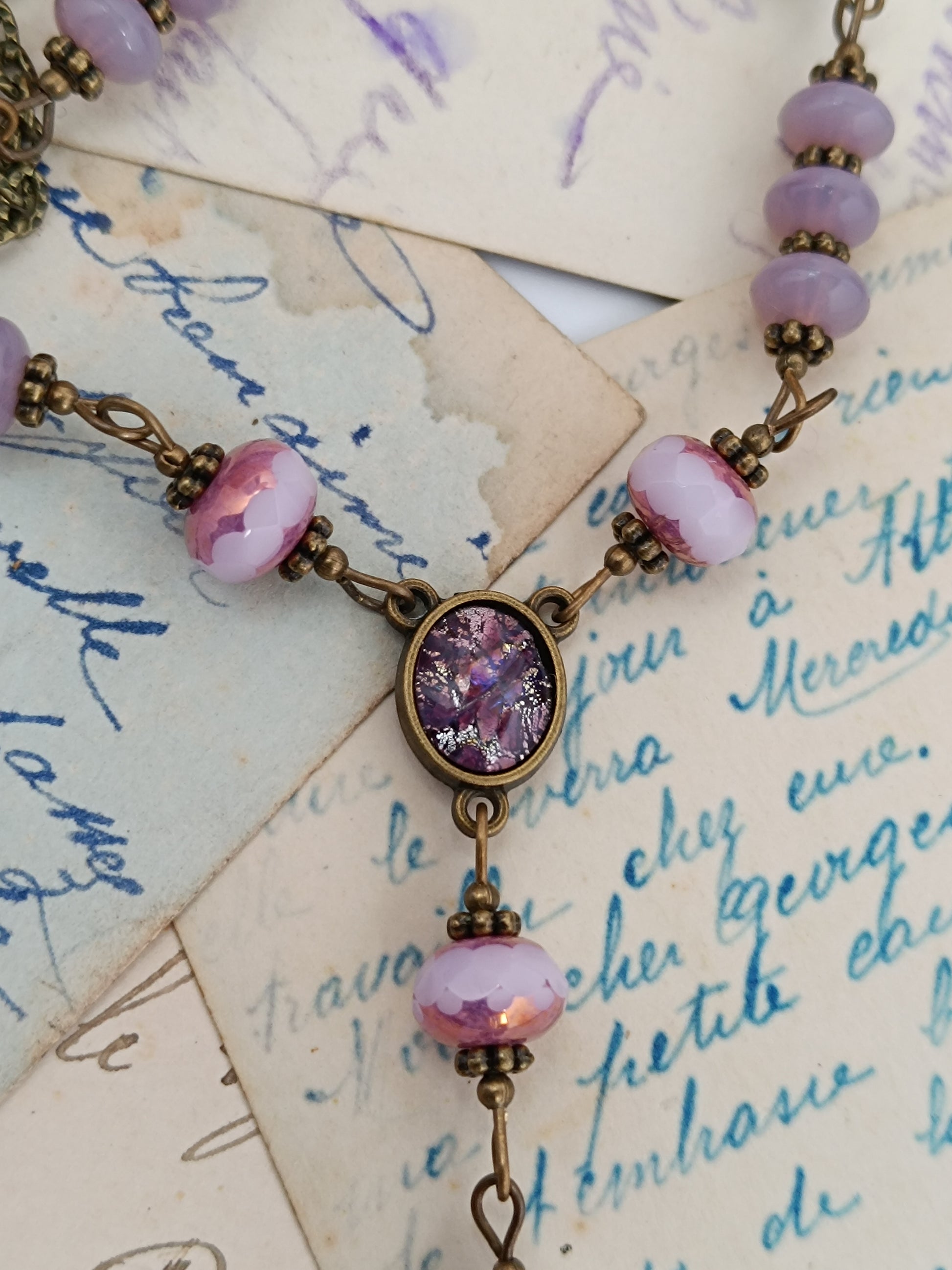 Détail du connecteur de collier vintage : petit cabochon en verre Silver Foil violet, perles opaline roses et laiton antique.