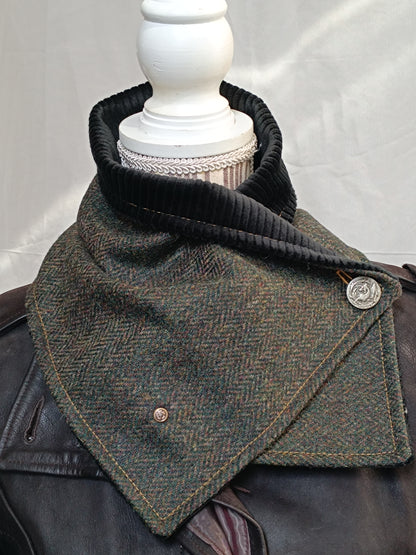 Écharpe boutonnée col de bénitier en laine à chevrons vert, brun et ocre, doublée velours côtelé noir. Photo prise en intérieur pour restituer fidèlement les couleurs sans lumière artificielle. Boutons métal décoratifs, dont un dragon vintage. Accessoire artisanal chaud et élégant, réalisé dans notre atelier de l’Oise.