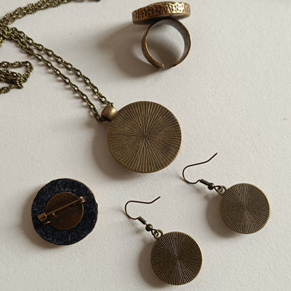 Vue de dos d'une parure de bijoux en bronze antique au motif circulaire texturé, comprenant collier, boucles d’oreilles, broche et bague ouverte. Style rétro artisanal inspiré des bijoux vintage.