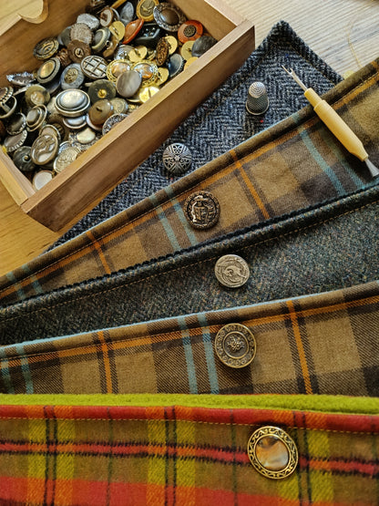 Présentation de plusieurs modèles en cours d’assemblage dans l’atelier : lainages à chevrons ou tartan, boutons vintage en métal gravé, nacre ou résine, chacun déjà associé à son tissu. Un aperçu du travail préparatoire, entre sélection minutieuse et composition textile. Accessoires faits main au style féerique, bohème ou cottagecore, réalisés dans notre atelier de l’Oise.