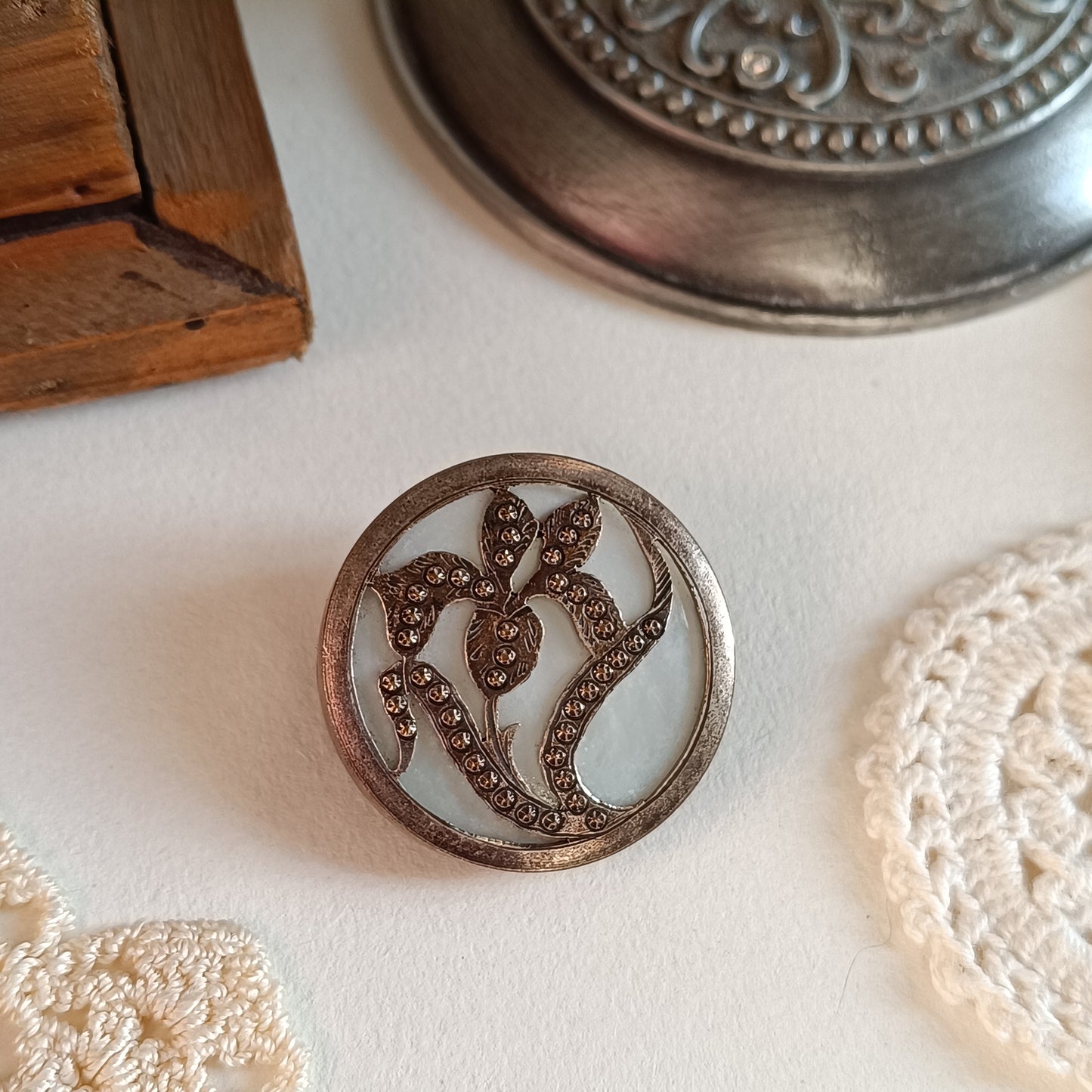 Découvrez cette broche confectionnée à partir d'un bouton de nacre français des années 1930. Métal texturé bronze, diamètre 3 cm. Accessoire élégant et rare par Nathalie Aucoudesanges.