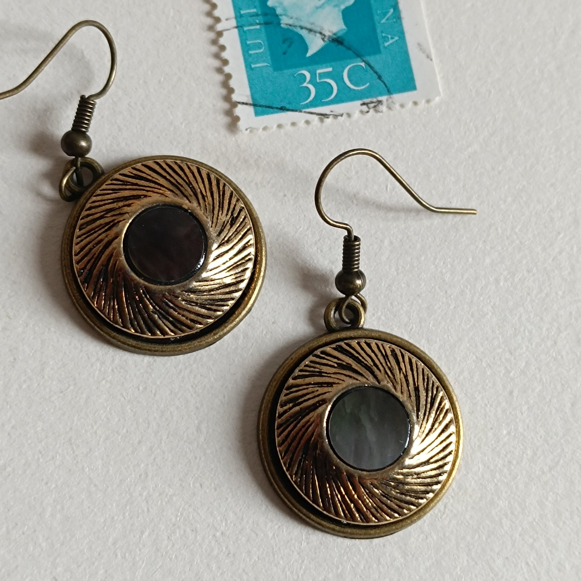 Paire de boucles d’oreilles rétro en bronze antique avec cabochons de nacre ronds et motif texturé, style vintage inspiré des boutons anciens. Bijoux artisanaux uniques.
