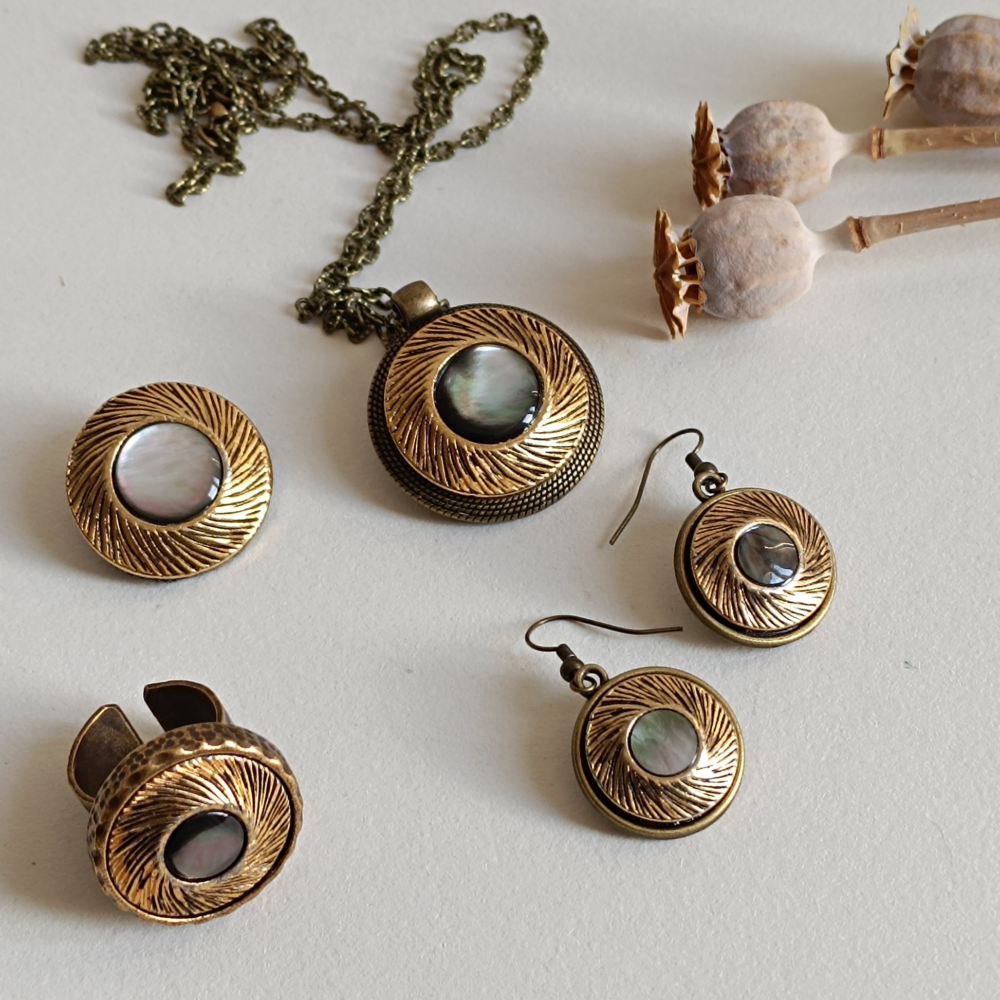 Parure de bijoux vintage français en bronze antique avec boutons anciens en nacre irisée, comprenant collier sautoir, bague réglable, boucles d’oreilles et broche, présentée sur fond clair avec pavots secs. Ensemble artisanal unique au style rétro et romantique.